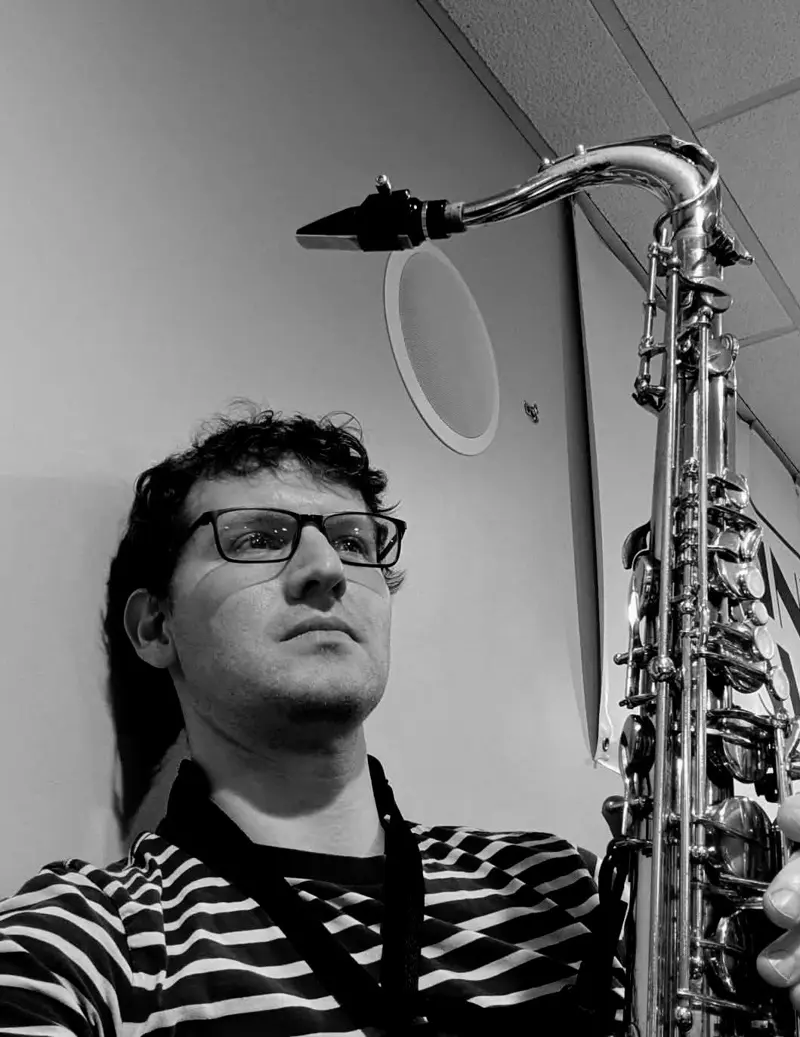 Black-and-white portrait of the saxophonist holding a tenor saxophone